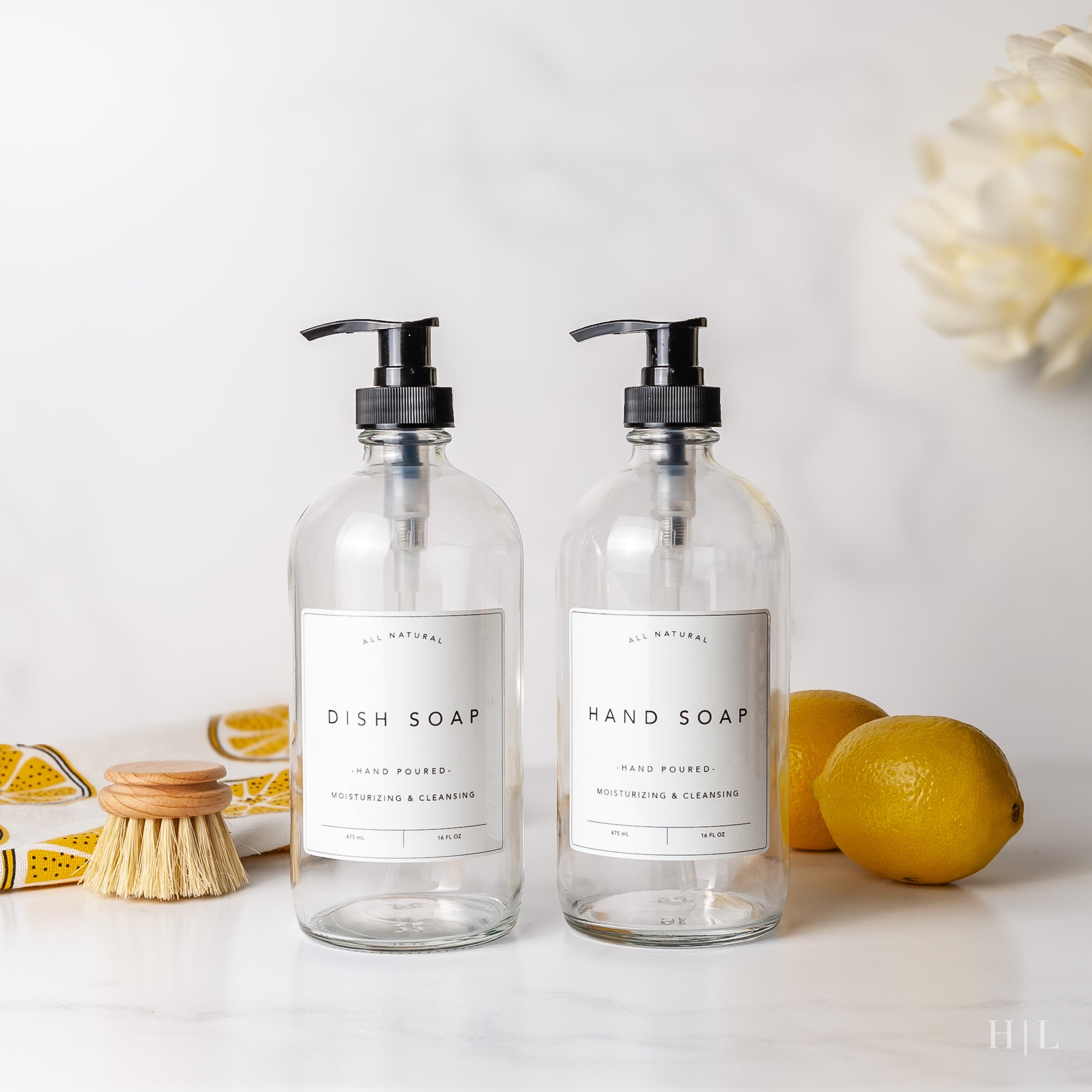 two soap dispensers sitting on a counter next to lemons