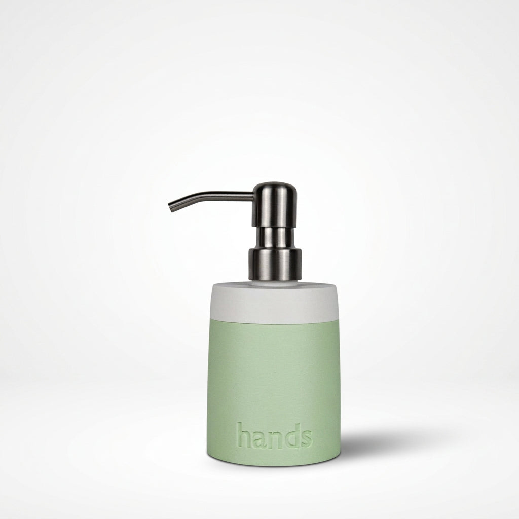 A minimalist hands dispenser with a matte pastel green body, a white collar, and a brushed silver metal pump, shown on a clean white background.