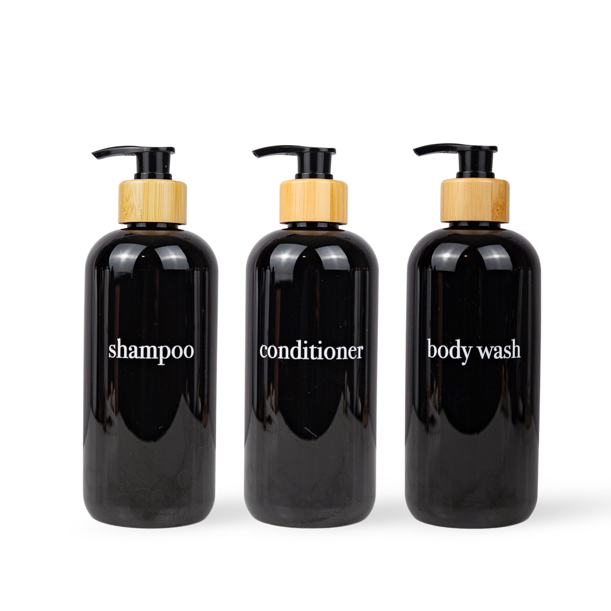 Three black bottles labeled 'shampoo', 'conditioner', and 'body wash' with wooden pumps on a white background.