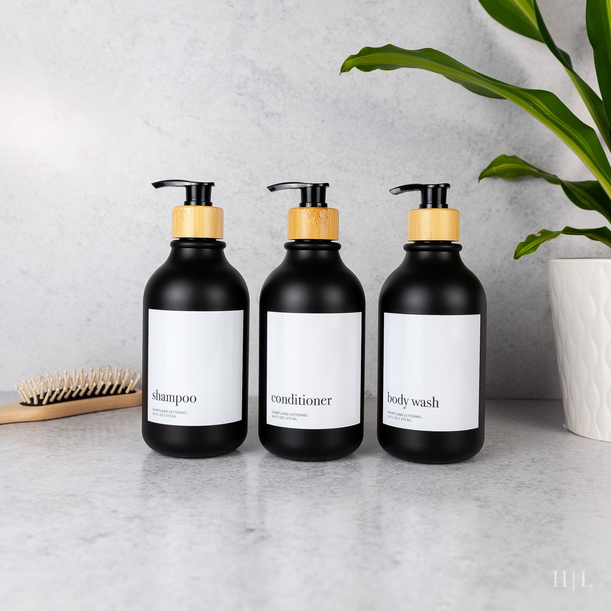 three bottles of hand soap next to a brush