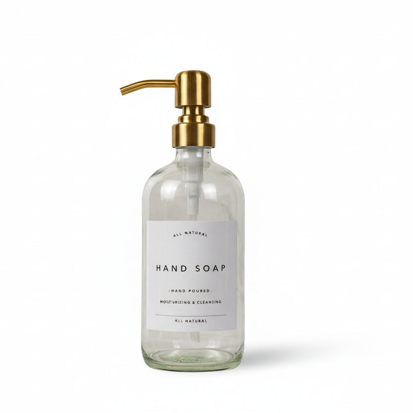 Clear glass hand soap bottle with gold pump on a white background