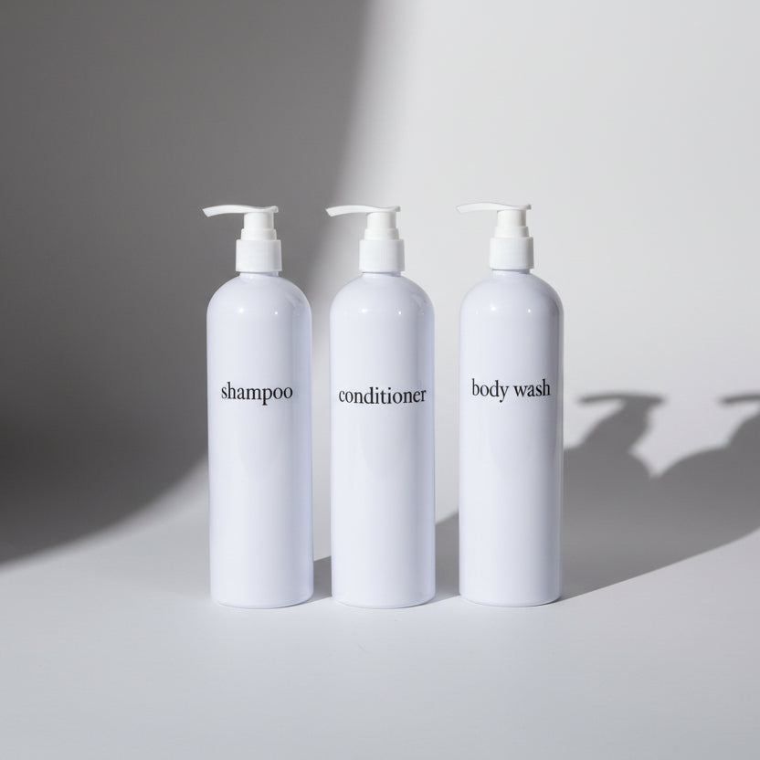 Three white bottles labeled 'shampoo', 'conditioner', and 'body wash' on a white background