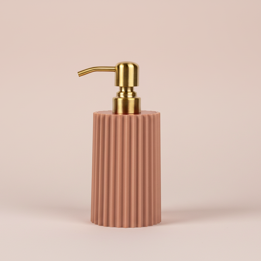 rose gold ribbed soap dispenser with gold pump on a rose colored background