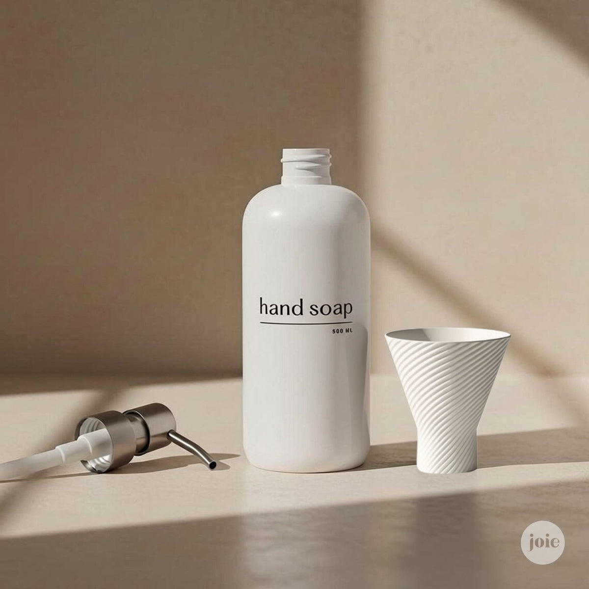 A matte white hand soap bottle labeled 'hand soap' with a matching white funnel and a silver-and-white pump dispenser, arranged on a beige surface with soft shadows.