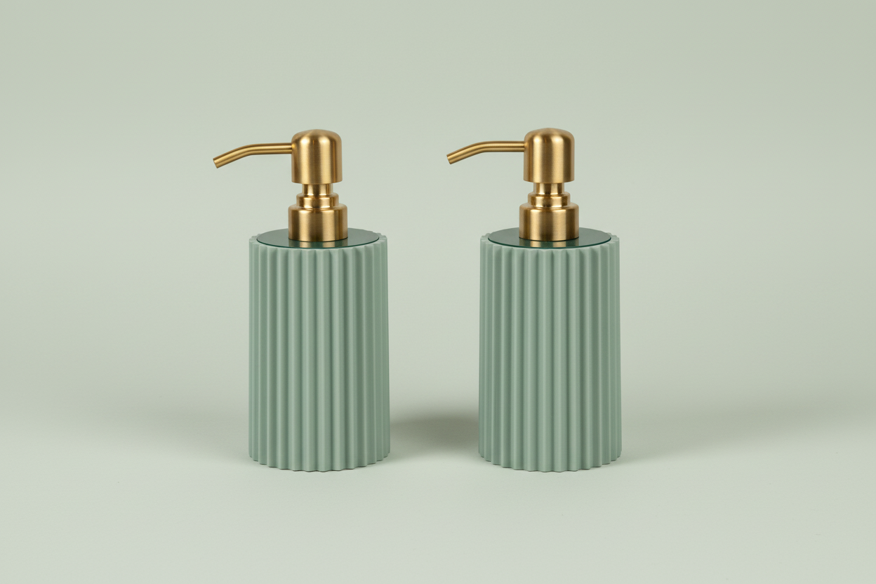 Two sage green ribbed soap dispensers with gold pumps on a light gray background