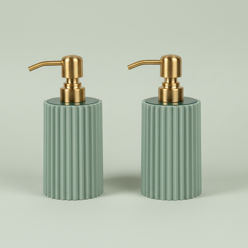 Two sage green ribbed soap dispensers with gold pumps on a light gray background