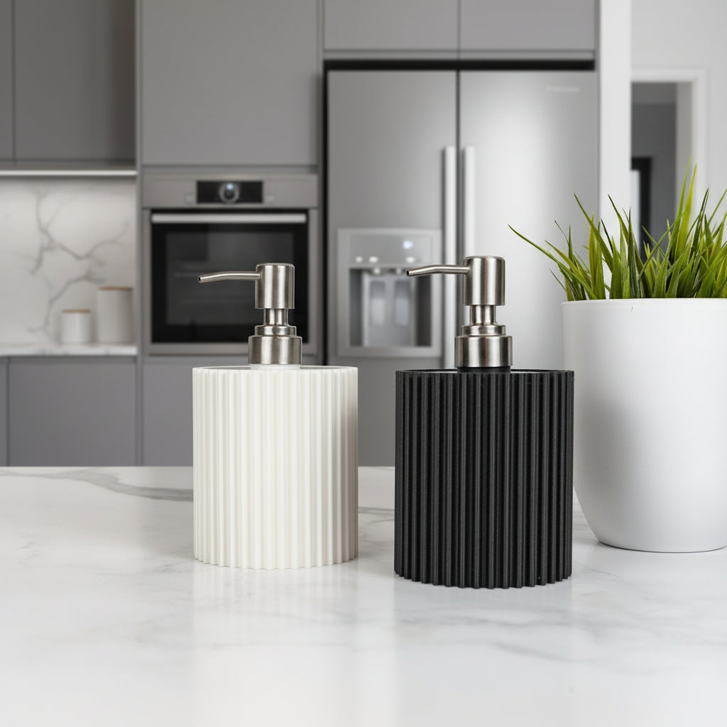 Two ribbed soap dispensers, one white and one black, on a marble surface with a plant in the background.