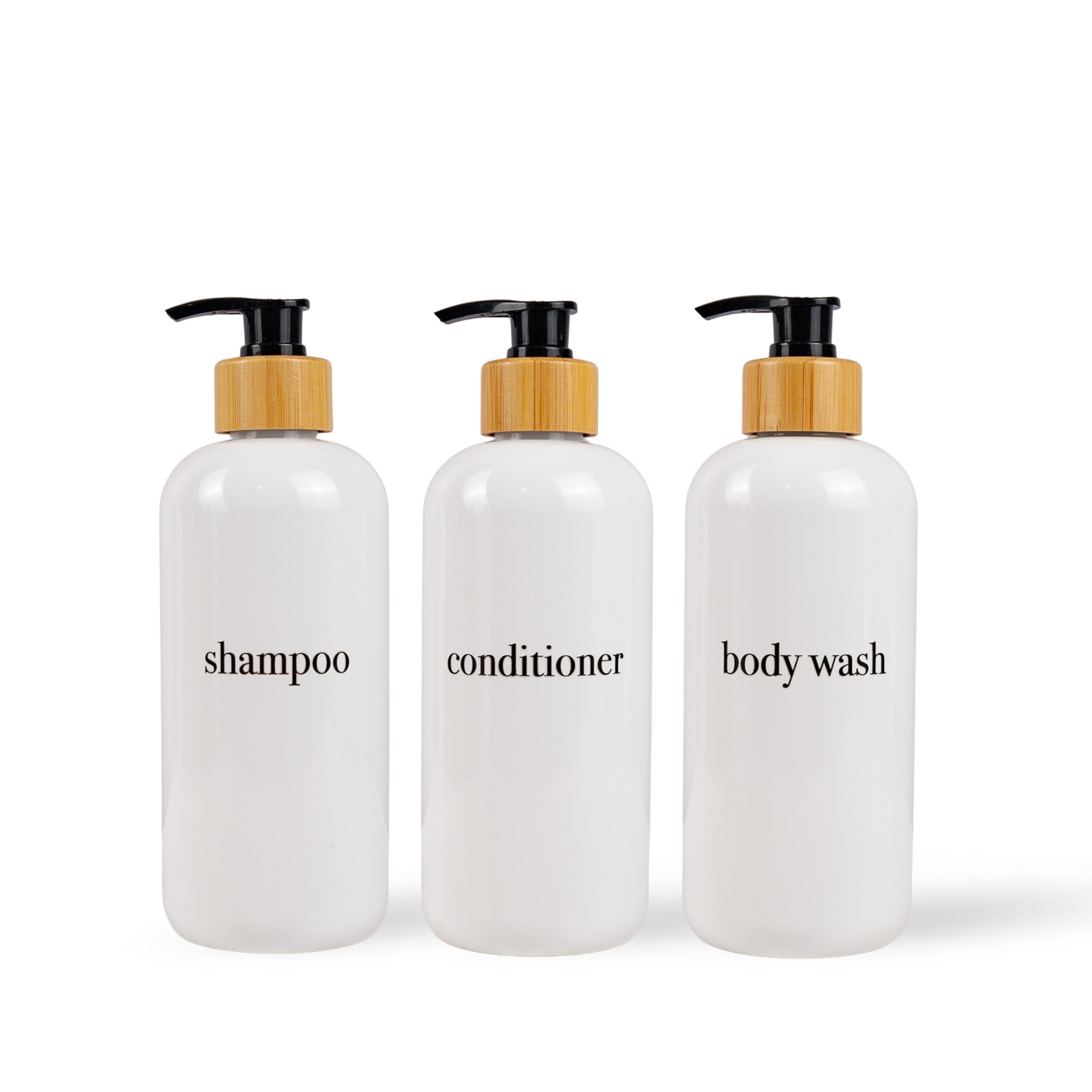 Three white bottles labeled 'shampoo', 'conditioner', and 'body wash' with bamboo pumps on a white background.